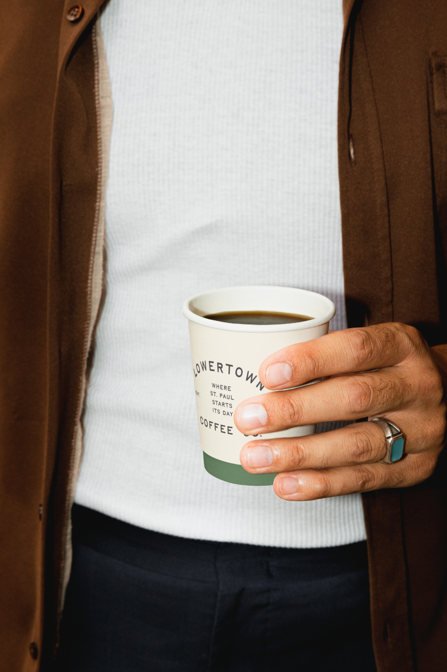 Man holding a coffee cup with a simple logo design on it
