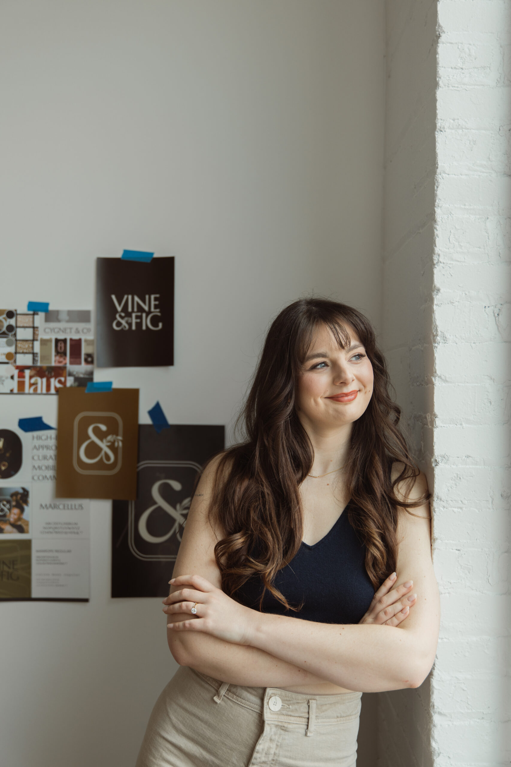 Brand and web designer in branding photos with portfolio taped to the wall